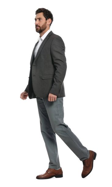 Handsome man in suit walking on white background - Photo, image