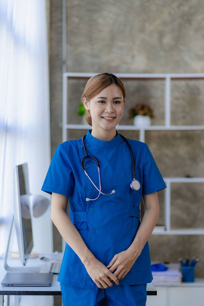 Розумна і приваблива азіатська лікарка готова до операції. красива жінка в синьому одязі і стояча медична та медична концепція в офісі лікаря. - Фото, зображення