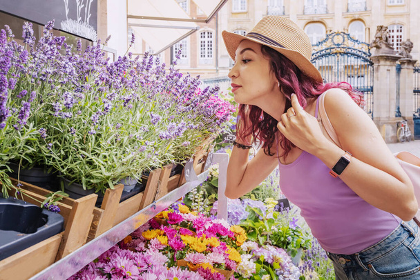 Happy girl buyer and a client choose lavender bouquets and flowers in pots at markets and florist shop on a city street - Φωτογραφία, εικόνα