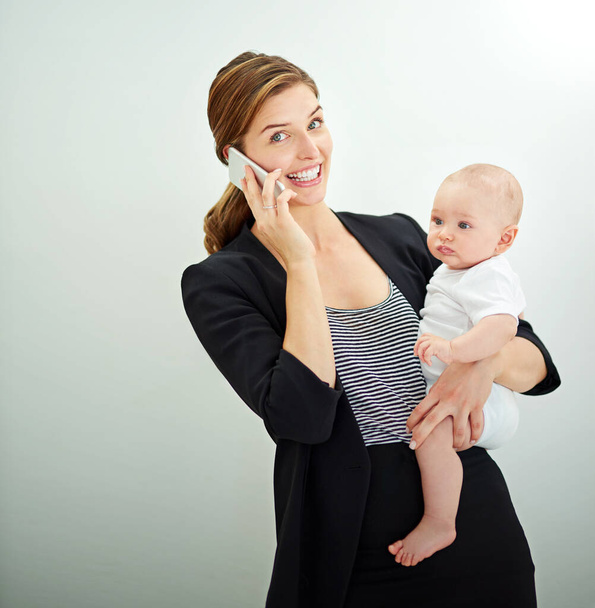 Bebeğim için çok çalışmak buna değer. Başarılı genç bir iş kadını telefonda konuşurken sevimli bebeğini taşıyor. - Fotoğraf, Görsel