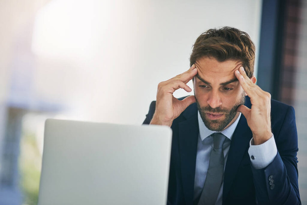 Te veel deadlines komen eraan. een jonge zakenman op zoek gestresst tijdens het werken in een kantoor - Foto, afbeelding