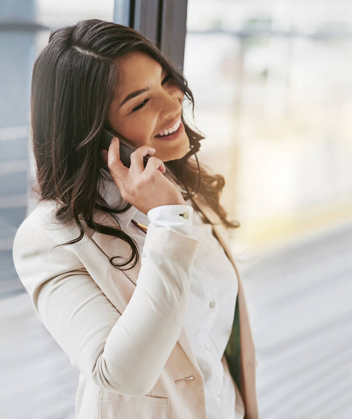 Там, чтобы удовлетворить потребности своих клиентов. молодая деловая женщина разговаривает по мобильному телефону в офисе - Фото, изображение