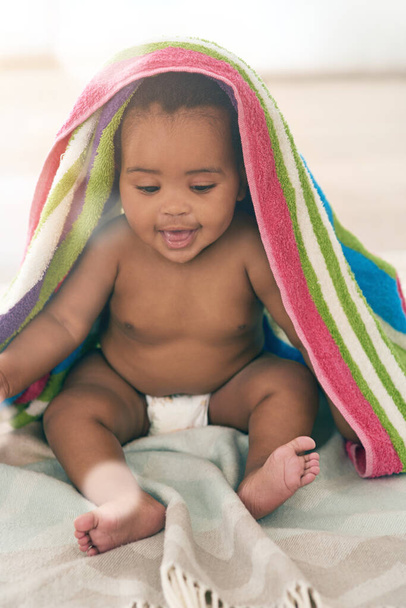 Είναι τόσο γλυκιά με το μωρό. ένα αξιολάτρευτο κοριτσάκι καλυμμένο με μια πολύχρωμη κουβέρτα στο σπίτι - Φωτογραφία, εικόνα
