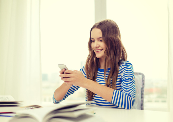 smiling student girl with smartphone and books - Valokuva, kuva