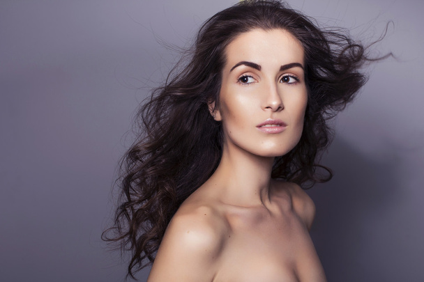 Beautiful brunette woman with clear fresh skin and curly hair on - 写真・画像