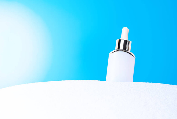 Escena burlona con tubo cosmético blanco sobre una arena blanca contra el cielo azul. Presentación del producto o anuncio del paquete. - Foto, imagen