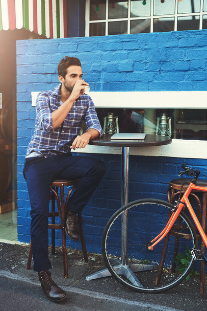 Где я могу расслабиться и работать. красивый молодой человек сидит в кафе на тротуаре - Фото, изображение