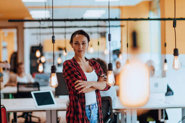 Жіночий бос, виконавчий директор позує в сучасному стартап-офісі, перебуваючи в оточенні її колег, команди
 - Фото, зображення