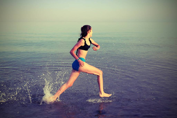 young girl runs training by the sea with old toned  effect in summer - Photo, Image