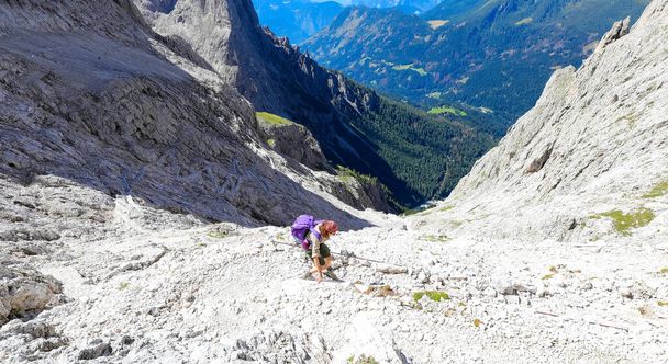 Young woman walks on the trail of the Dolomites in the European Alps of the mountain range called Pale Group in Italy - Photo, Image
