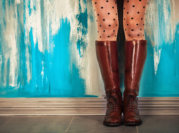 Γυναικεία πόδια σε καφέ δερμάτινες μπότες κοντά στον τοίχο - Φωτογραφία, εικόνα