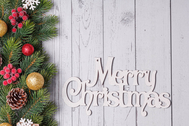 mooie takken van een kerstboom met kegels en speelgoed op een witte houten achtergrond met de inscriptie Merry Christmas close-up - Foto, afbeelding