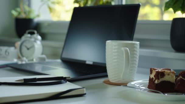 Arbeitsplatz im Home Office. Tisch mit Laptop, Notizbuch und heißem Kaffee neben Fenster im Wohnzimmer. - Filmmaterial, Video