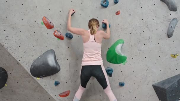 ボルダリングジムで壁に登る女性。女性登山訓練は、ボルダリングクライミングの壁にかかっている。アクティブライフスタイルと極端なスポーツコンセプト. - 映像、動画