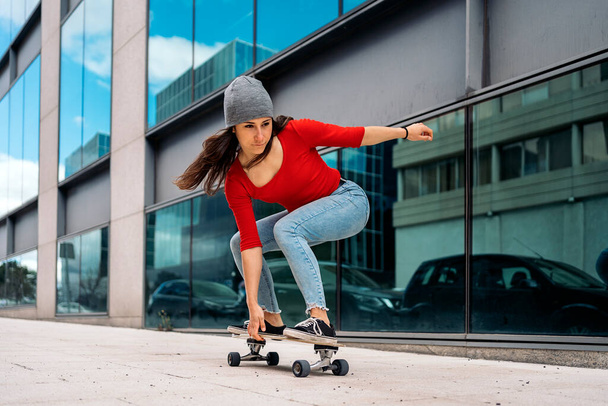 Cool skater woman practicing with her longboard in the city and having fun. - Photo, image