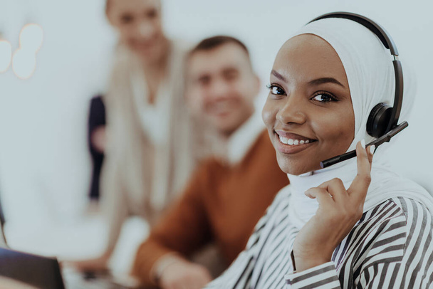 African American Muslim woman with hijab and headset working as customer support in a modern office - Фото, изображение