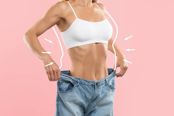 Unerkennbare schlanke Frau in übergroßen Jeans beim Größenvergleich nach Gewichtsverlust, junge schlanke Frau mit gezeichneter, fetter Silhouette um den Körper, isoliert über rosa Hintergrund stehend, Collage - Foto, Bild