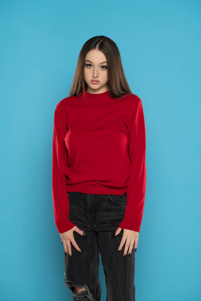 Menina bonito em blusa vermelha e jeans preto isolado no fundo do estúdio azul - Foto, Imagem