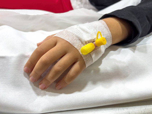 Gefäßzugang an der Hand eines jungen kranken Mädchens am Krankenhausbett - Foto, Bild