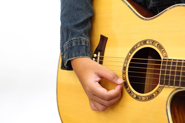 Concentre-se nas mãos da criança ou adolescente tocando guitarra acústica em fundo branco. Aprender e relaxar conceito. - Foto, Imagem