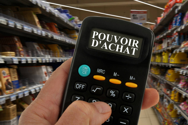 Kaufkraftkonzept mit Taschenrechner in der Hand und verschwommenen Supermarktregalen im Hintergrund  - Foto, Bild