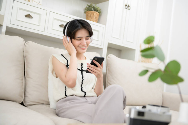 An Asian teenager wearing headphones enjoying music at home  - Foto, Imagem