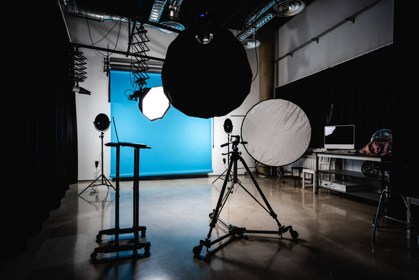 Sisustus moderni tilava valokuva studio roikkuu sininen tausta valokeila ja kannettava tietokone ennen ammunta - Valokuva, kuva