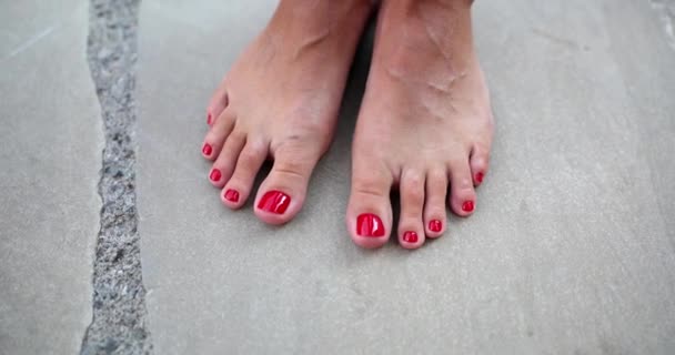 Femme belles jambes saines avec pédicure rouge se tenir sur carreau gros plan. Soins de la peau et des pieds - Séquence, vidéo