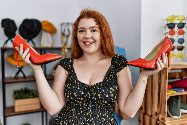 Young redhead woman high heel shoes shopping at clothing store - Photo, Image
