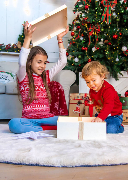 Les enfants ouvrent des cadeaux de Noël sous le sapin. Concentration sélective. Enfant.. - Photo, image