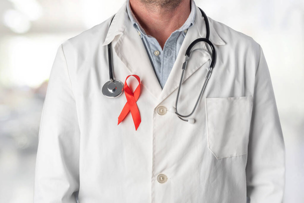 Medico con un nastro rosso sul petto, simbolo della Giornata Mondiale dell'AIDS. Supporto del personale sanitario alle persone affette da HIV. Prevenzione e lotta contro il virus dell'AIDS - Foto, immagini