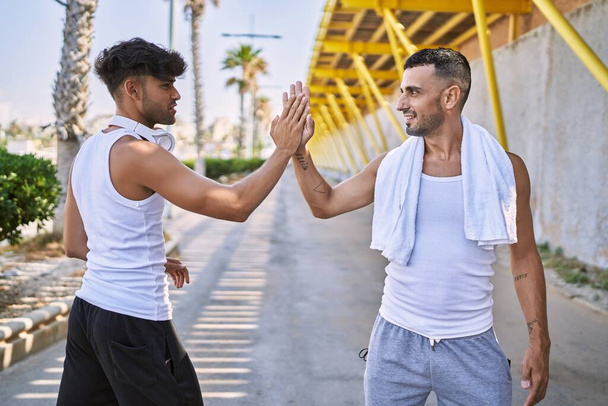 Két spanyol férfi vigyorog magabiztosan, felemelt kézzel az utcán. - Fotó, kép
