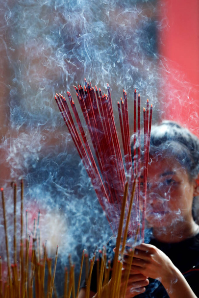Ong Bon Pagode, taoistischer Tempel. Frau betet mit brennenden Räucherstäbchen. Ho Chi Minh Stadt. Vietnam. - Foto, Bild