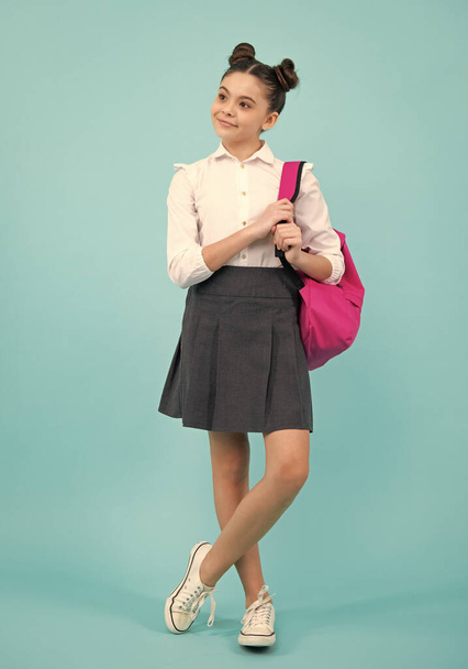 Schoolgirl in school uniform with school bag. Schoolchild, teen student on blue isolated background. Happy teenager, positive and smiling emotions of teen girl - Foto, Imagen