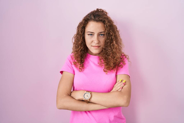 Young caucasian woman standing over pink background skeptic and nervous, disapproving expression on face with crossed arms. negative person.  - Foto, Imagen