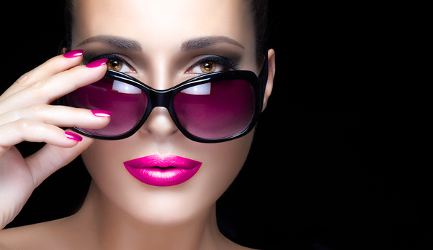 Cara de mujer de primer plano en gafas de sol rosadas de gran tamaño. Maquillaje y Mani
 - Foto, Imagen