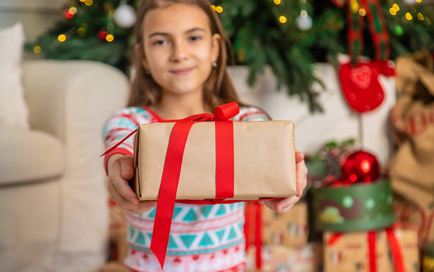 Gyerekek a karácsonyfa közelében egy ajándékkal. Szelektív fókusz. Kölyök!. - Fotó, kép