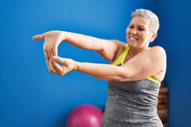 Middle age woman smiling confident stretching at sport center - Foto, immagini