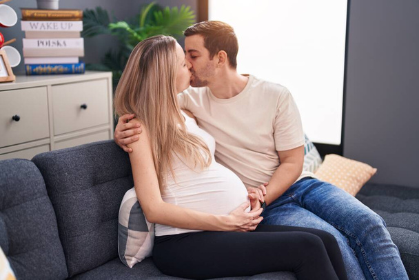 Uomo e donna coppia in attesa di bambino che si abbracciano a vicenda baciandosi a casa - Foto, immagini