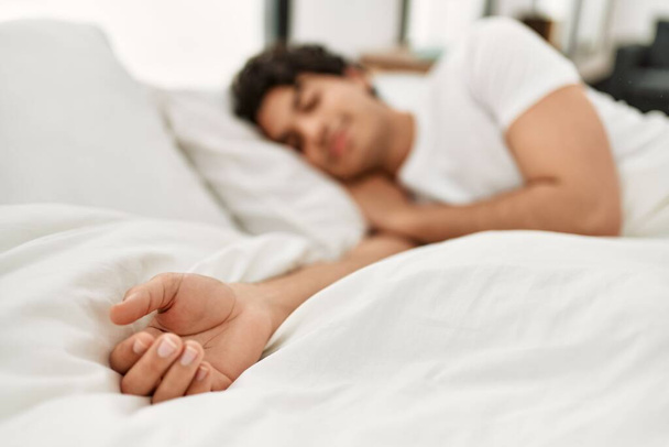 Young hispanic man sleeping lying on the bed at bedroom. - Фото, изображение