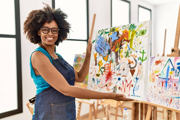 Jovem afro-americana sorrindo confiante segurando desenhar no estúdio de arte - Foto, Imagem