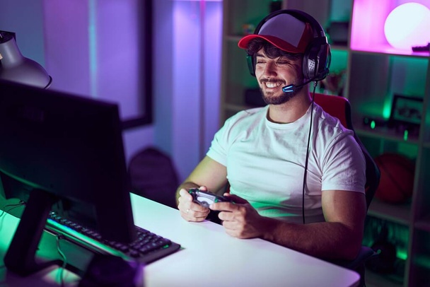 Fiatal spanyol férfi streamer mosolygós magabiztos videojáték Gamin szoba - Fotó, kép