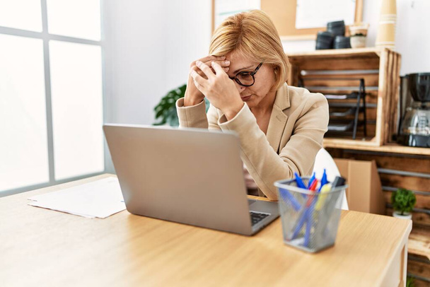 Keski-ikä blondi nainen työskentelee vakava ilme toimistossa - Valokuva, kuva