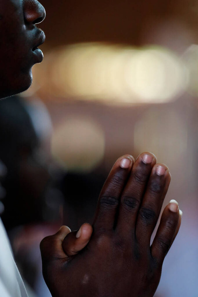 Iglesia africana. Misa católica dominical. Hombre rezando. Primer plano en las manos. Agbonou Koeroma. Togo..  - Foto, imagen