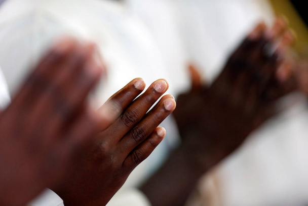 Iglesia africana. Misa católica dominical. Hombre rezando. Primer plano en las manos. Agbonou Koeroma. Togo..  - Foto, imagen
