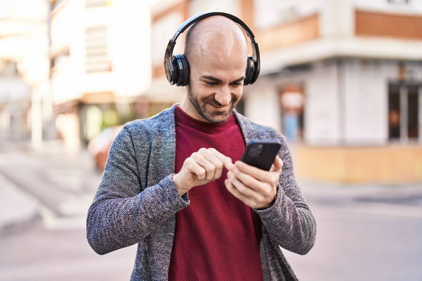 Молодой человек уверенно улыбается, слушая музыку на улице - Фото, изображение