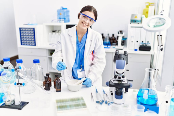 Fiatal spanyol nő, tudományos egyenruhát visel, laborban dolgozik. - Fotó, kép