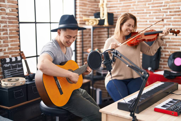 Άνδρες και γυναίκες μουσικοί που παίζουν βιολί και κλασική κιθάρα στο στούντιο μουσικής - Φωτογραφία, εικόνα