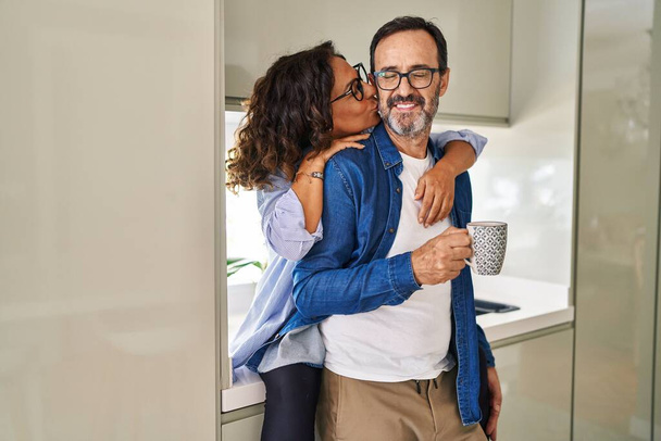 Középkorú spanyol pár csókolózik és ölelkeznek, kávét isznak a konyhában. - Fotó, kép