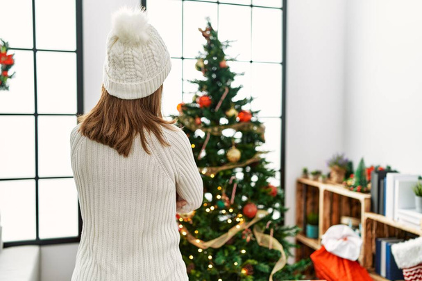 Middle age caucasian woman on back view looking christmas tree at home - Photo, Image